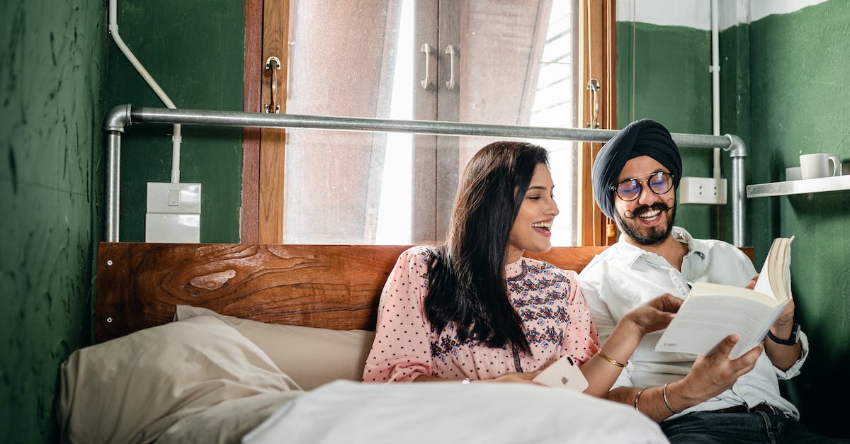 Is it cheaper to book excursions locally for South Africa? - Happy Indian couple of husband in turban and glasses with handlebar mustache and good looking wife reading book and laughing while resting on big wooden bed Is it cheaper to book excursions locally for South Africa? - Happy Indian couple of husband in turban and glasses with handlebar mustache and good looking wife reading book and laughing while resting on big wooden bed