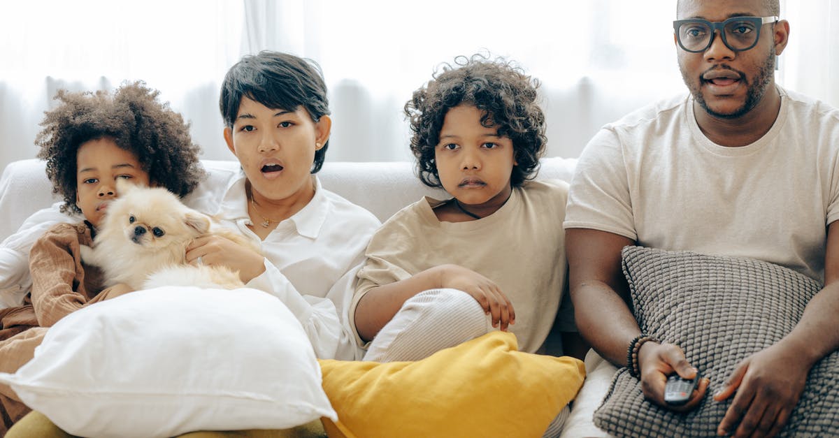 Is it illegal to watch violent films on an airplane? - Interested multiracial family watching TV on sofa together with dog Is it illegal to watch violent films on an airplane? - Interested multiracial family watching TV on sofa together with dog