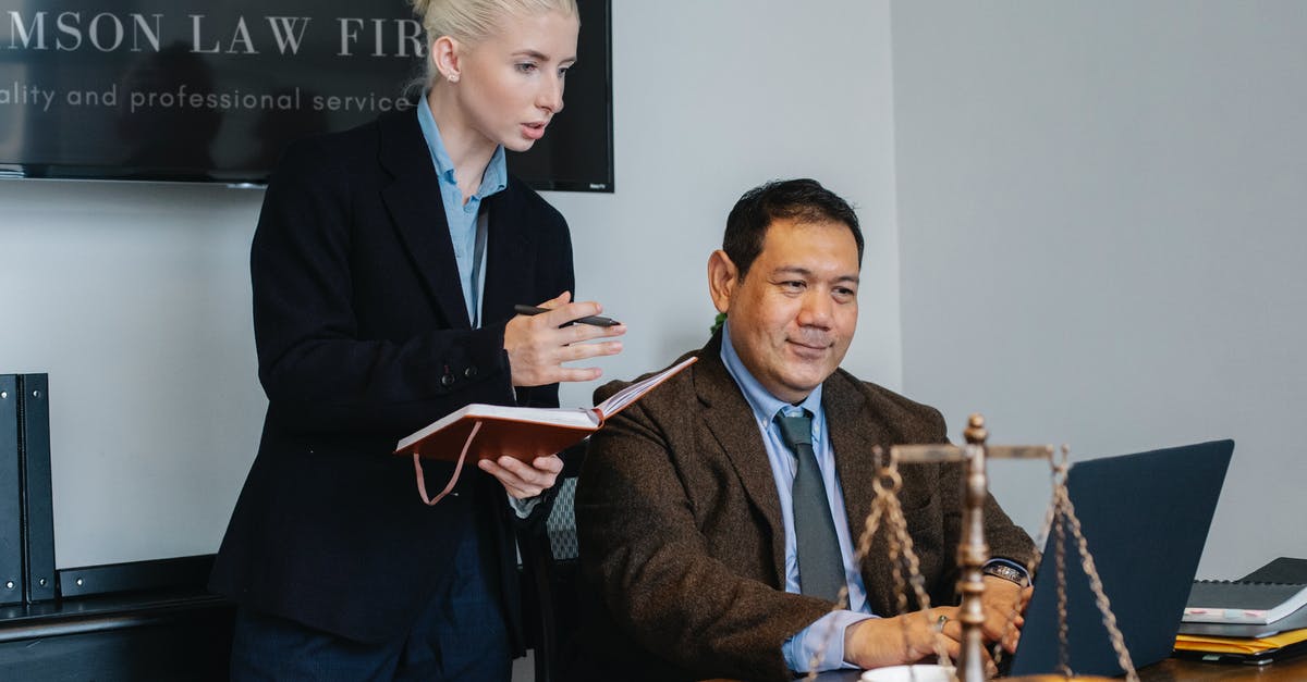 Is it legal to take photos at the airport? - Ethnic male lawyer showing document on laptop to young female colleague Is it legal to take photos at the airport? - Ethnic male lawyer showing document on laptop to young female colleague