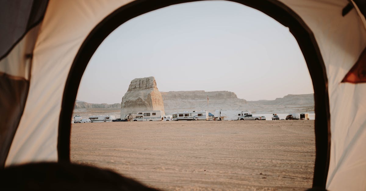 Is it legal to wild camp (with a car) in Ireland? - View of sandy beach with distanced cars parked on seaside with rocky cliffs through opened tent in nature with cloudless sky Is it legal to wild camp (with a car) in Ireland? - View of sandy beach with distanced cars parked on seaside with rocky cliffs through opened tent in nature with cloudless sky