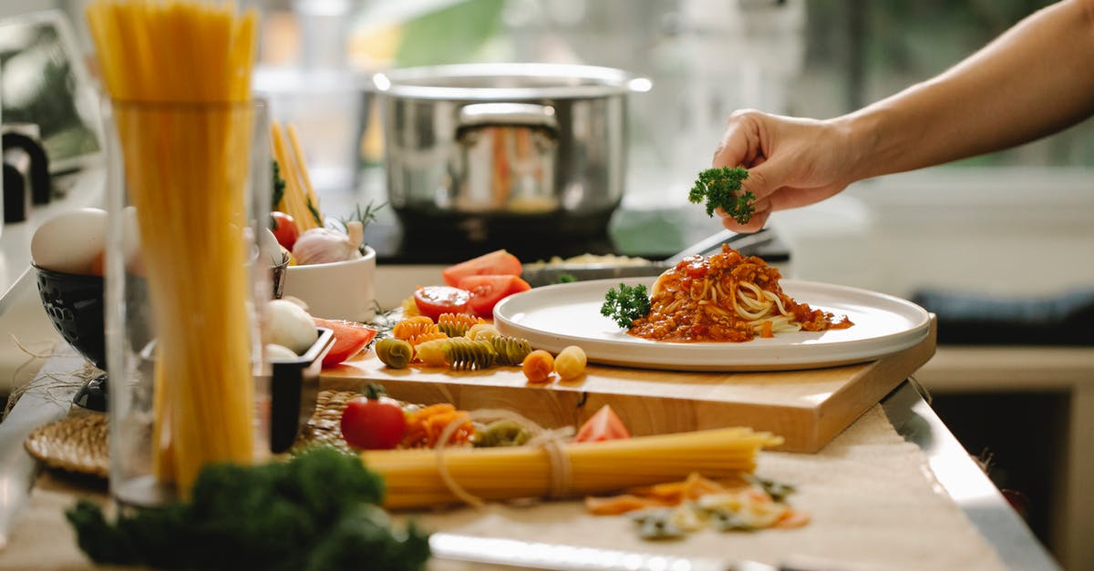 Is it offensive to the chef/host to finish all food on your plate in Italy? - Crop anonymous chef adding parsley to spaghetti with tomato and meat while cooking lunch in kitchen Is it offensive to the chef/host to finish all food on your plate in Italy? - Crop anonymous chef adding parsley to spaghetti with tomato and meat while cooking lunch in kitchen