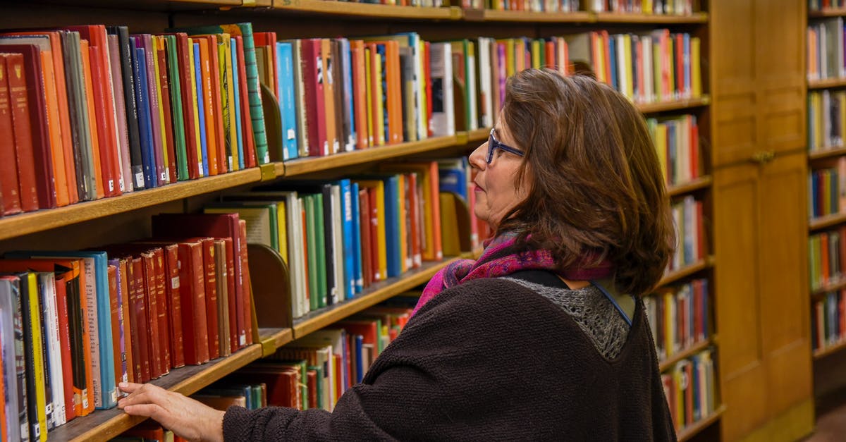 Is it possible to aggregate different hotel bookings in one search? - Woman choosing book in public library Is it possible to aggregate different hotel bookings in one search? - Woman choosing book in public library