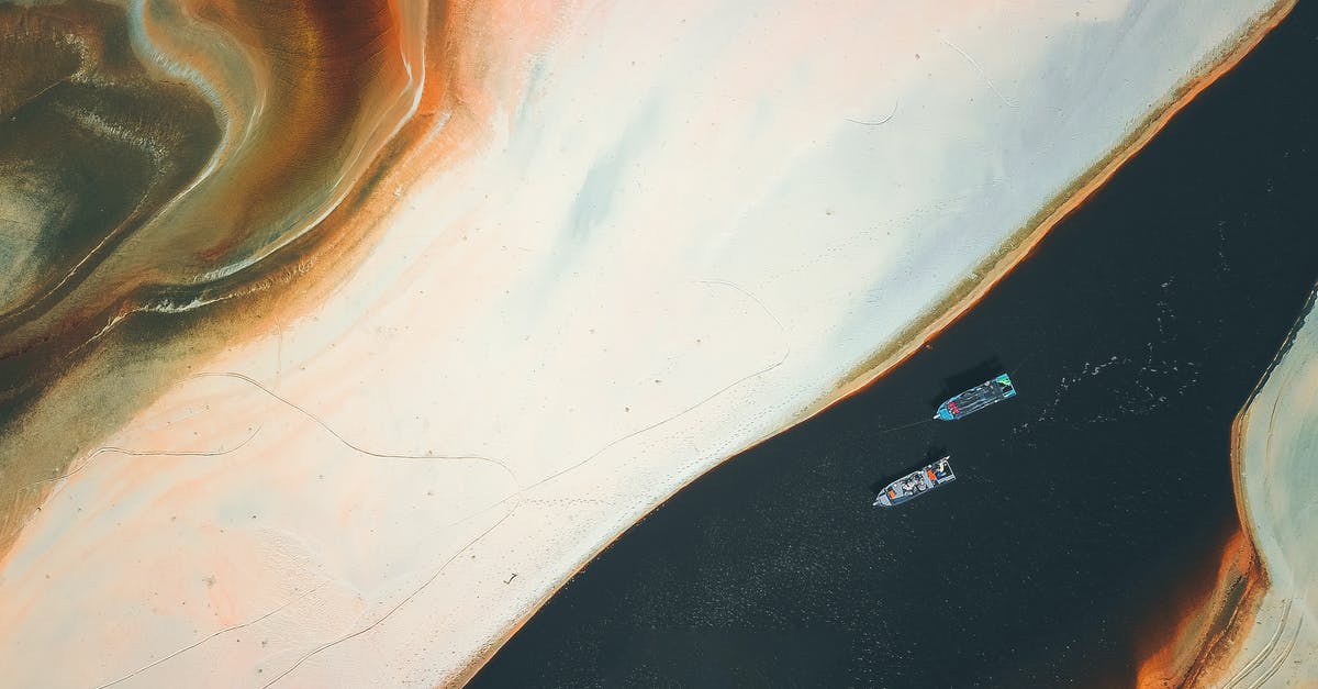 Is it possible to go by ship from Djibouti to Egypt? - Aerial view of colorful textured sandy shore near floating boats in water in sunny day Is it possible to go by ship from Djibouti to Egypt? - Aerial view of colorful textured sandy shore near floating boats in water in sunny day