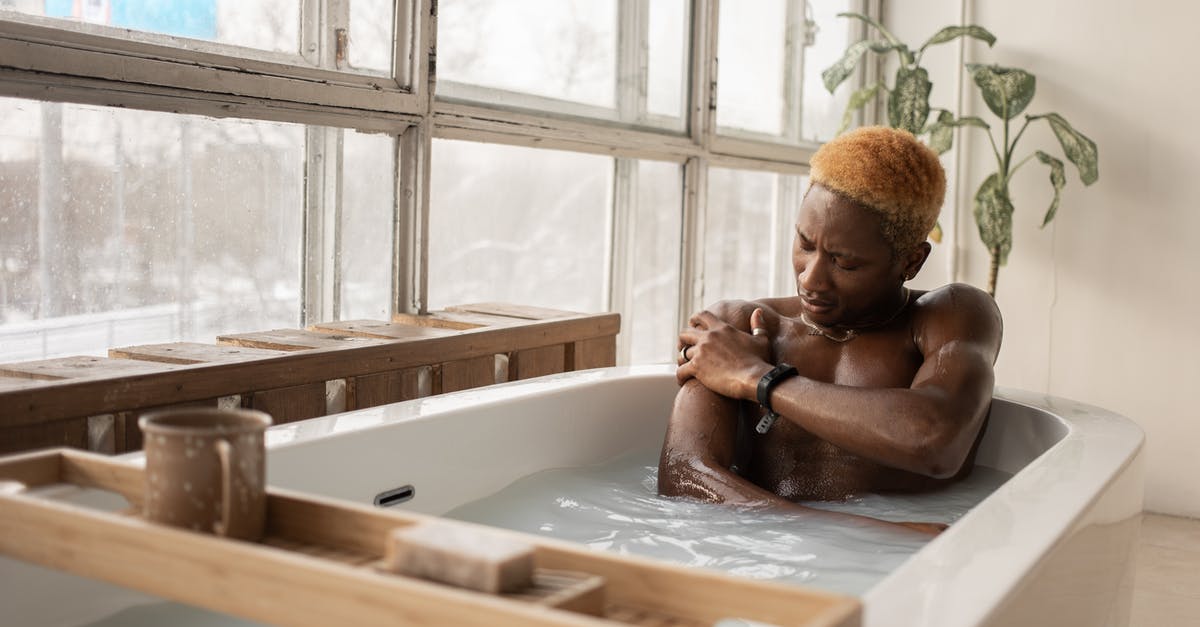 Is it possible to share an individual hotel room? - Young African American man with dyed hair and accessory sitting in bathtub full of water in light room with shabby window frames Is it possible to share an individual hotel room? - Young African American man with dyed hair and accessory sitting in bathtub full of water in light room with shabby window frames