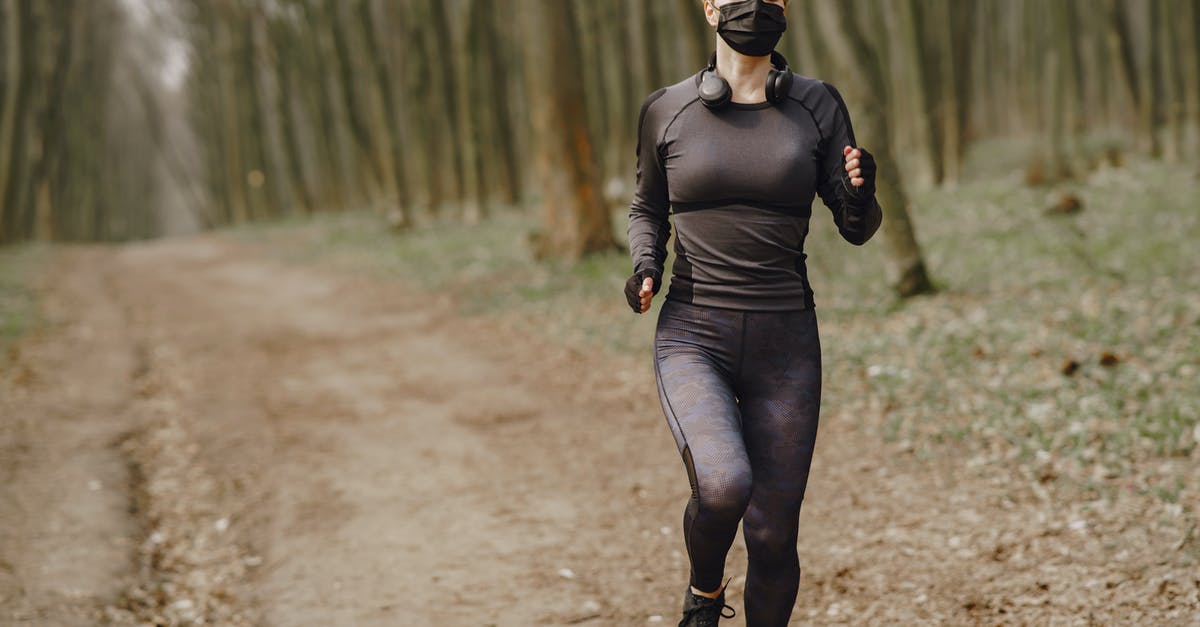 Is it safe to arrive at Amboseli National Park (Kenya) at night? [closed] - Fit woman in sportswear and mask jogging along forest alley during virus outbreak