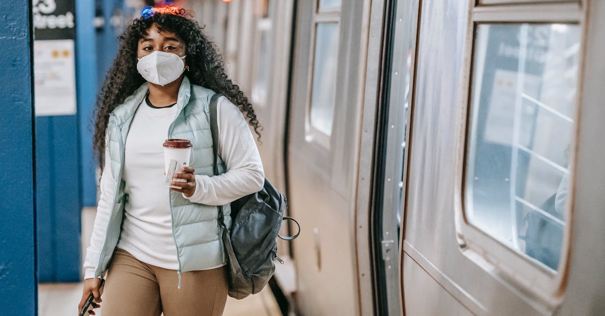 Is it safe to go to Içmeler, Turkey now? - Calm black woman with coffee wearing medical mask standing in metro Is it safe to go to Içmeler, Turkey now? - Calm black woman with coffee wearing medical mask standing in metro