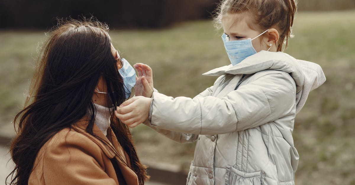 Is it safe to park a motorbike on the street at night Spain? [closed] - Cute little girl in mask helping put on medical mask for mom in sunglasses during stroll in park