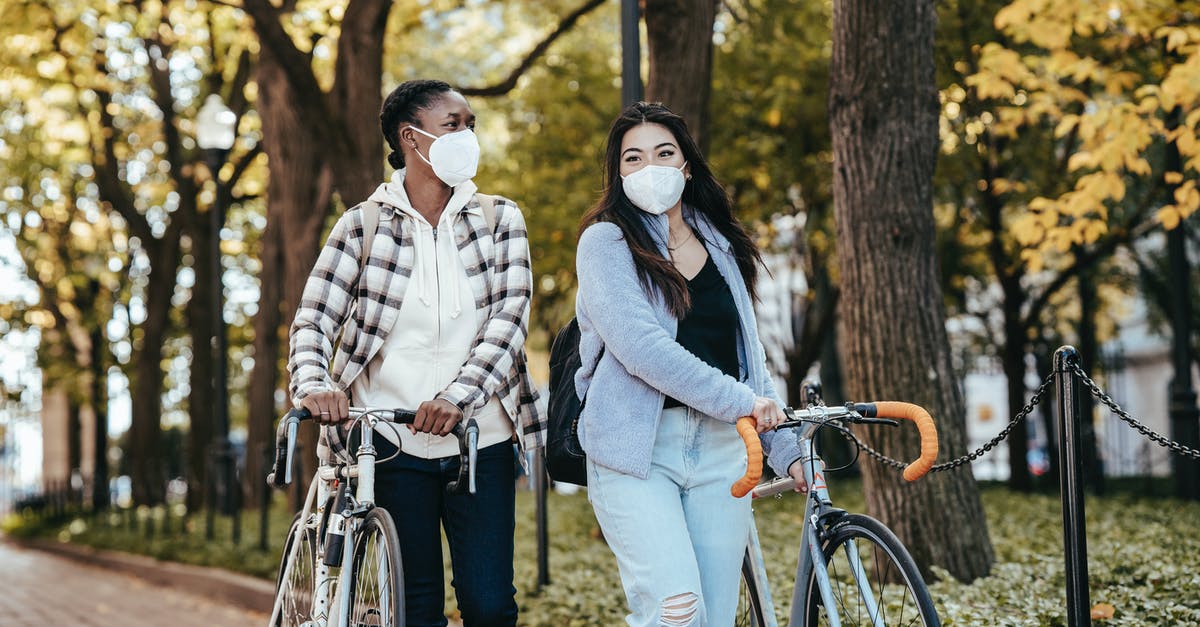 Is it safe to park hired 2 wheeler near Goa beaches? - Diverse girlfriends with bicycles walking on pavement in park Is it safe to park hired 2 wheeler near Goa beaches? - Diverse girlfriends with bicycles walking on pavement in park