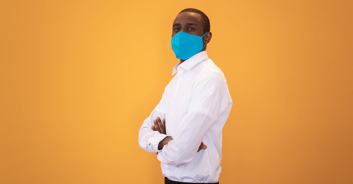 Is it safe to stand next to airport X-ray machines? - Black man in protective mask standing with crossed arms against yellow background Is it safe to stand next to airport X-ray machines? - Black man in protective mask standing with crossed arms against yellow background