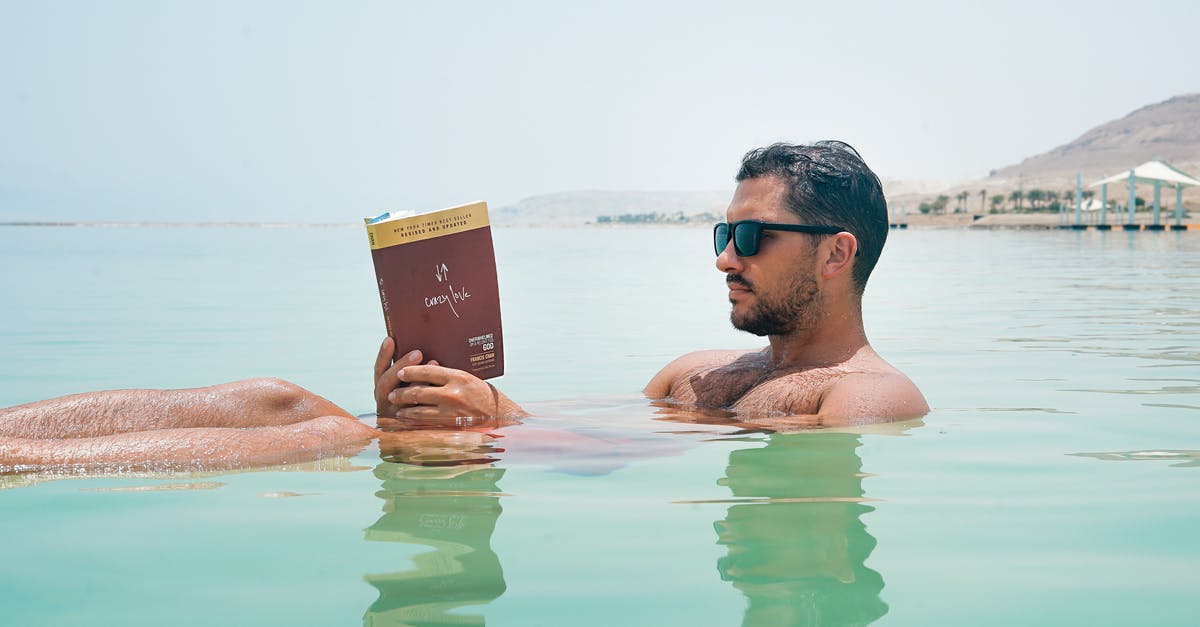 Is it true that with a Seaman's book you travel cheap? - Man Wearing Sunglasses Reading Book on Body of Water Is it true that with a Seaman's book you travel cheap? - Man Wearing Sunglasses Reading Book on Body of Water