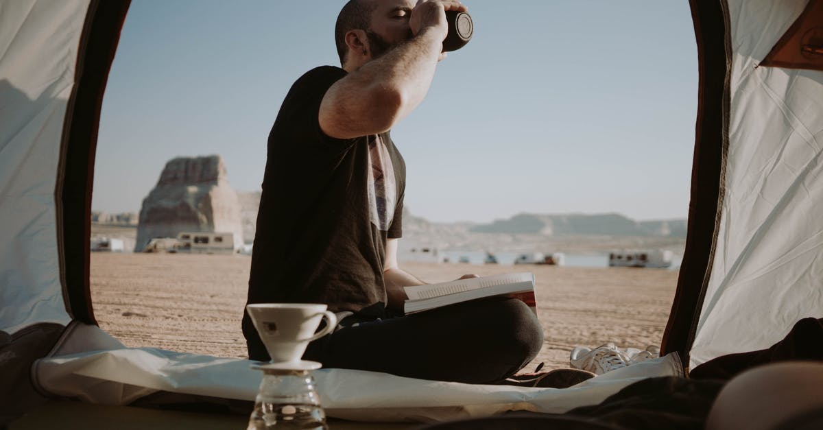 Is Khasan open to tourists? - Side view of male traveler sitting in tent with book near pour over cup while drinking hot beverage in nature during trip Is Khasan open to tourists? - Side view of male traveler sitting in tent with book near pour over cup while drinking hot beverage in nature during trip