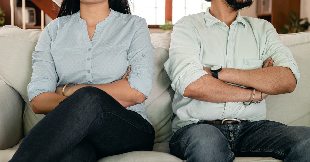 Is marriage certificate required to prove ties to home country? - Crop faceless young ethnic couple in casual wear sitting on couch with arms crossed keeping silence after scandal at home Is marriage certificate required to prove ties to home country? - Crop faceless young ethnic couple in casual wear sitting on couch with arms crossed keeping silence after scandal at home