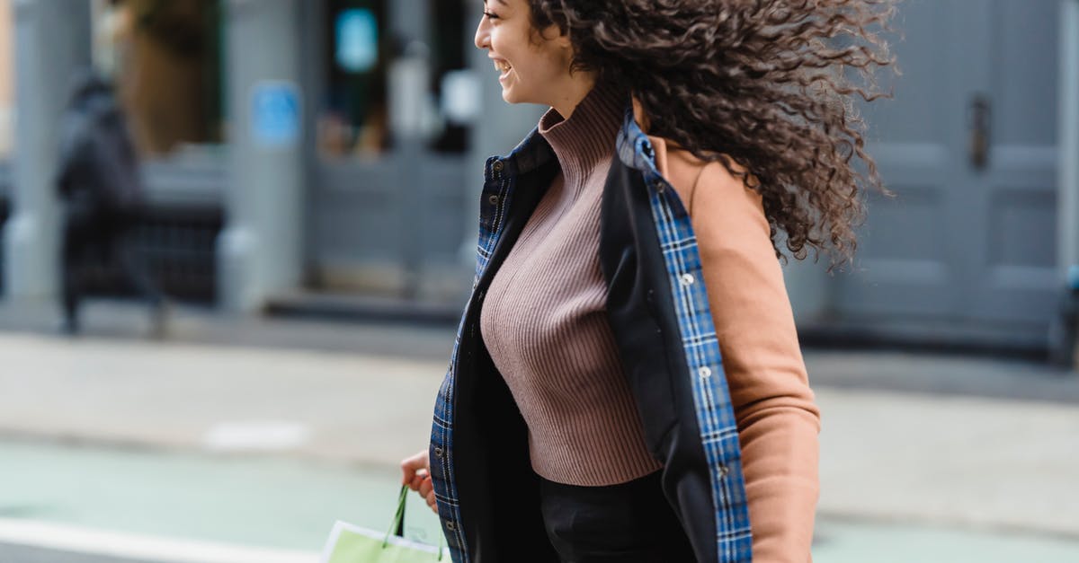 Is possible to cross the Bering Strait without flying? - Positive young ethnic female with flowing hair carrying shopping paper bags while quickly crossing road and looking away Is possible to cross the Bering Strait without flying? - Positive young ethnic female with flowing hair carrying shopping paper bags while quickly crossing road and looking away