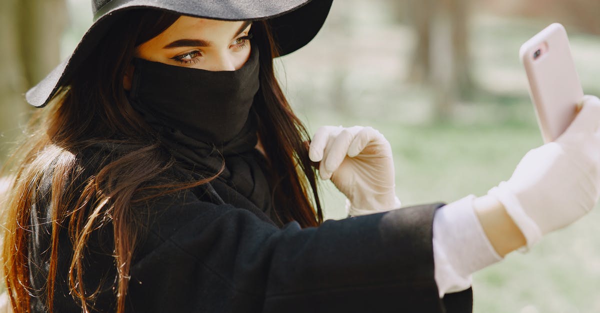 Is refund possible if I cannot take a (just rebooked) flight because of coronavirus bans? [duplicate] - Crop female in stylish outerwear and medical mask and gloves taking selfie on smartphone in park during walk on city street