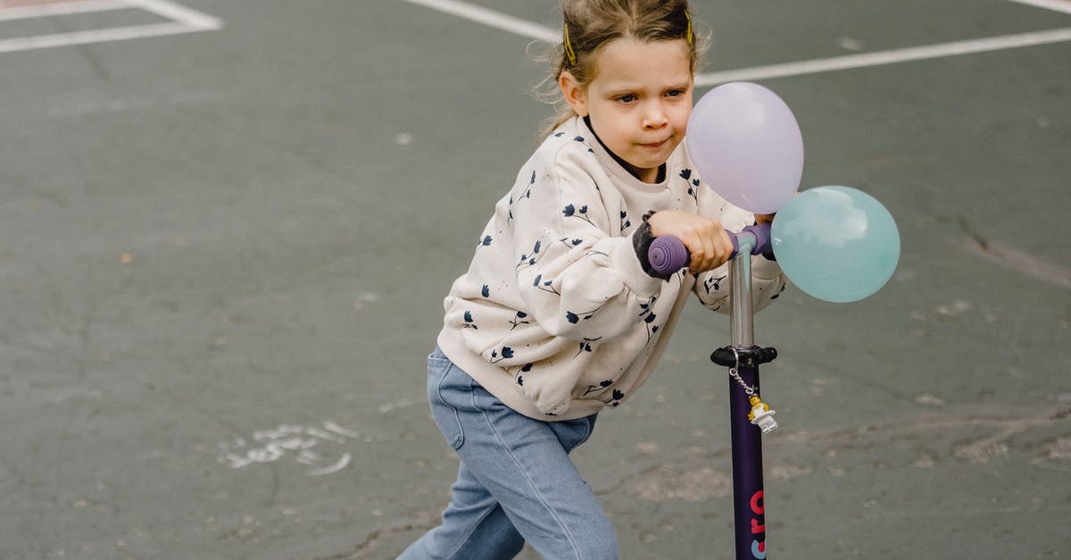 Is riding an electric scooter on pavement not tolerated in London? [closed] - Cute kid in trendy wear with ornament and balloons riding electric scooter while looking forward on sports ground
