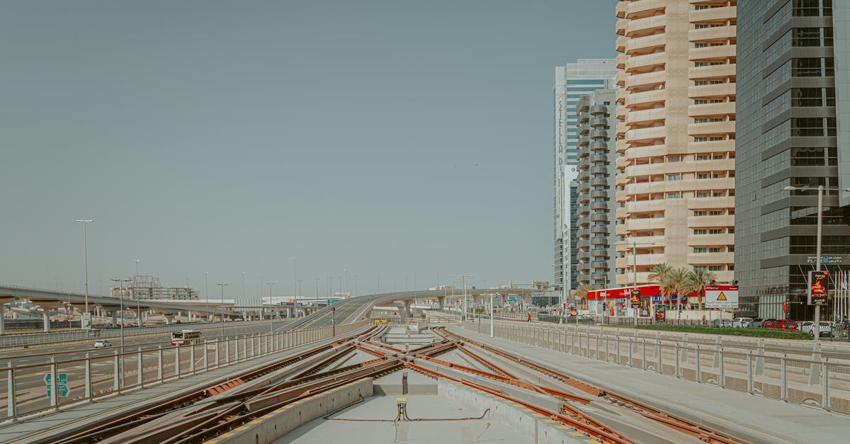 Is there a continuous highway or high-speed rail between Estonia to Poland? - Metro tracks running through modern city along flat asphalt road and tall buildings Is there a continuous highway or high-speed rail between Estonia to Poland? - Metro tracks running through modern city along flat asphalt road and tall buildings