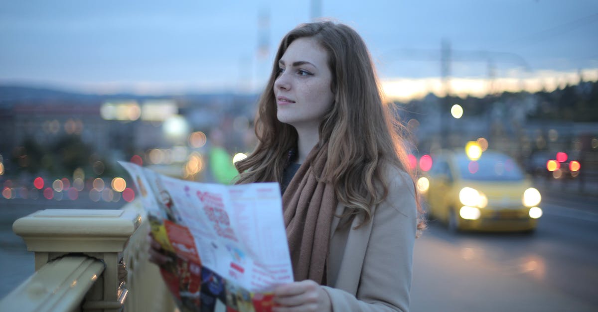 Is there a map that shows Austrian winter road closures? - Female traveler in warm clothes standing on street with map and looking away at dusk Is there a map that shows Austrian winter road closures? - Female traveler in warm clothes standing on street with map and looking away at dusk