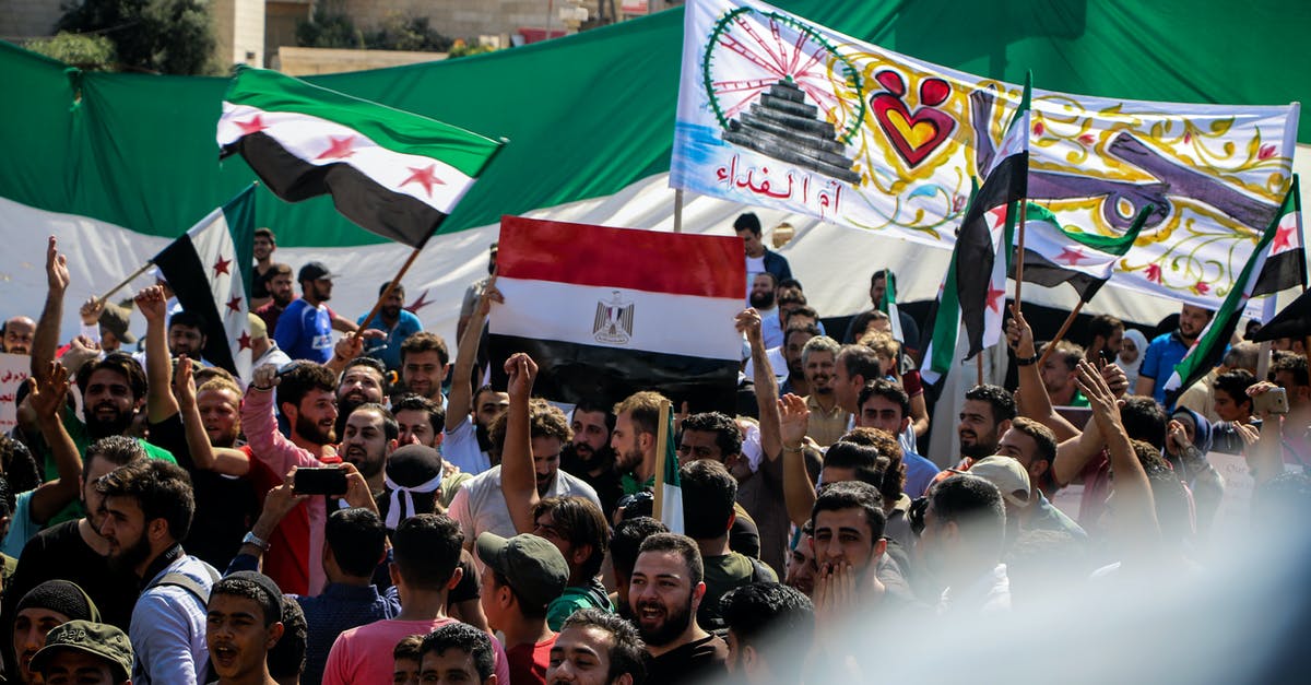 Is there a problem to use 2 passports, one for getting into country and another whilst coming back? [duplicate] - Crowd of demonstrators raising hands and showing posters and flags on protest in daytime