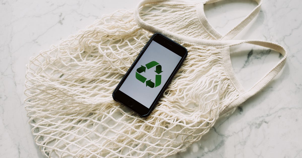 Is there a way to save on Hawaiian Airlines checked-bags fees? - Overhead of smartphone with simple recycling sign on screen placed on white eco friendly mesh bag on marble table in room Is there a way to save on Hawaiian Airlines checked-bags fees? - Overhead of smartphone with simple recycling sign on screen placed on white eco friendly mesh bag on marble table in room
