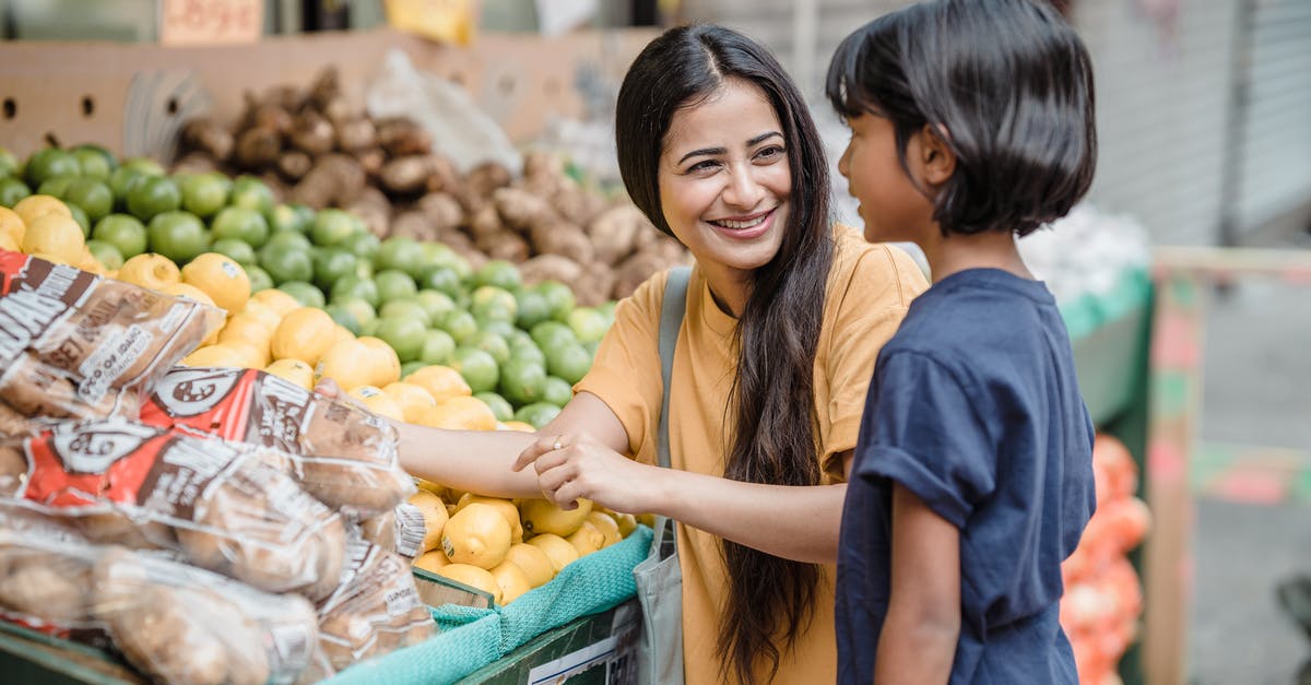 Is there an Indian food market in Montevideo? - Woman in Blue Crew Neck T-shirt Standing Beside Fruit Stand