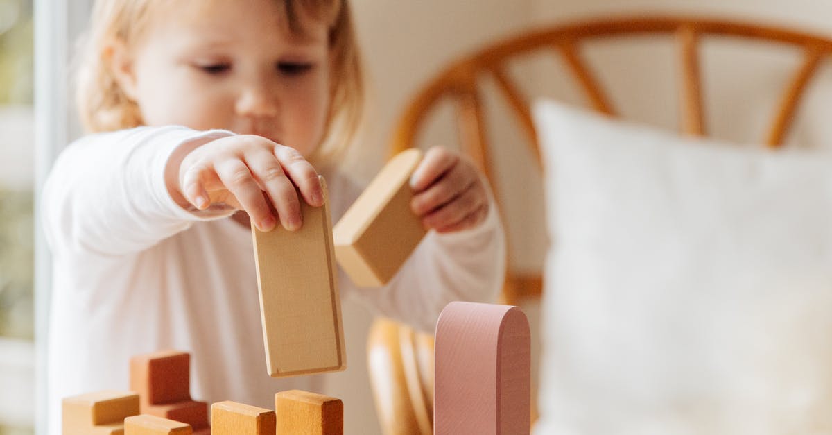 Is there an obligation to renew a small child's passport before its expiry date? - Cute little girl in white casual clothes standing near table and playing with wooden blocks while spending time at home