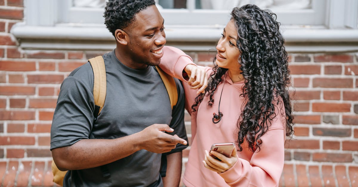 Is there an online resource listing magic shows in Central Europe? [closed] - Positive young ethnic female with long curly hair standing on street with arm on shoulder of cheerful black boyfriend and showing funny video on smartphone