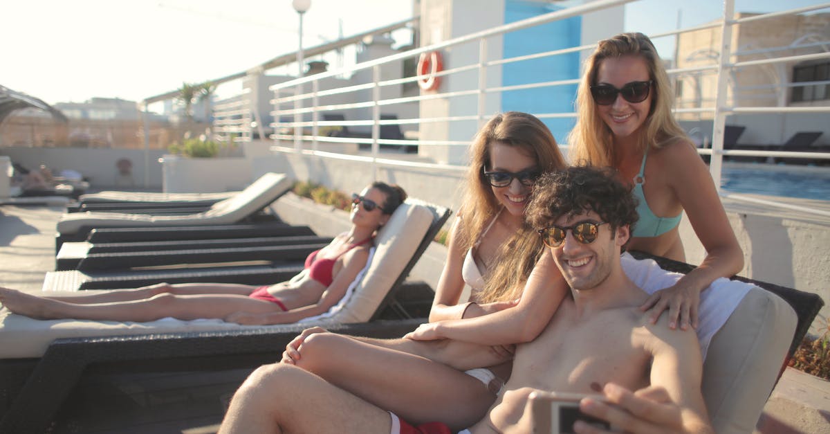 Is there any advantage of using a travel agent in this day and age? [duplicate] - Smiling young people in sunglasses and swimsuits sitting and taking selfie on mobile phone while relaxing together on sunny day
