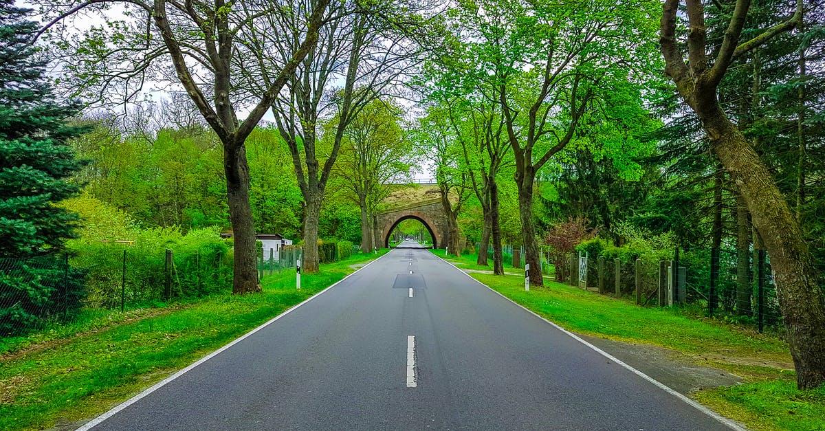 Is there any easy and cheap way to obtain an invitation to any Schengen zone country? - Narrow asphalt roadway with marking lines and arched tunnel far away between colorful trees with thick trunks and green grass in rural zone Is there any easy and cheap way to obtain an invitation to any Schengen zone country? - Narrow asphalt roadway with marking lines and arched tunnel far away between colorful trees with thick trunks and green grass in rural zone