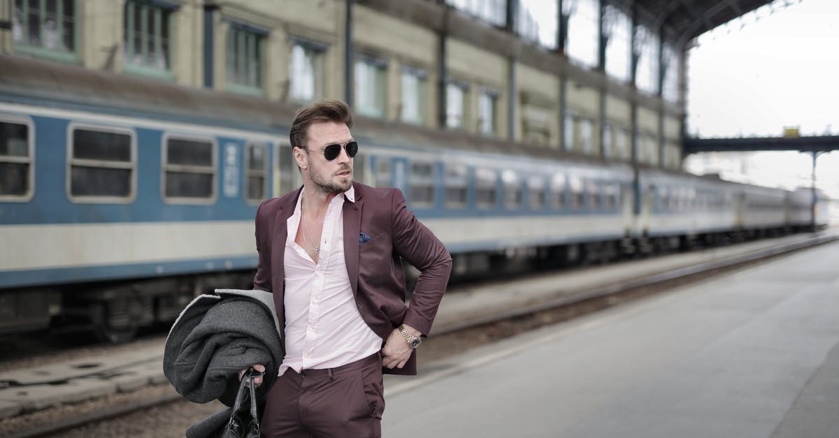 Is there luggage storage at train stations in Japan? - Confident trendy male traveler standing on railroad platform with coat and travel bag