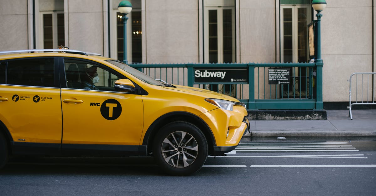 Is USA safe for Indians currently - Contemporary yellow taxi with driver in medical mask standing on empty road near modern building and subway station entrance during coronavirus pandemic in New York USA Is USA safe for Indians currently - Contemporary yellow taxi with driver in medical mask standing on empty road near modern building and subway station entrance during coronavirus pandemic in New York USA