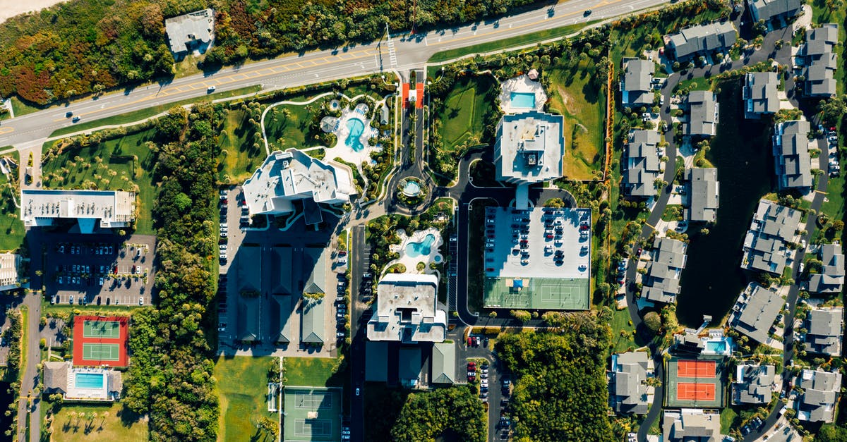 Islands and similar where visitors cannot take a car - Drone view of similar villas with red roofs located on street with parked colorful cars surrounded by green palm trees in tropical country Islands and similar where visitors cannot take a car - Drone view of similar villas with red roofs located on street with parked colorful cars surrounded by green palm trees in tropical country