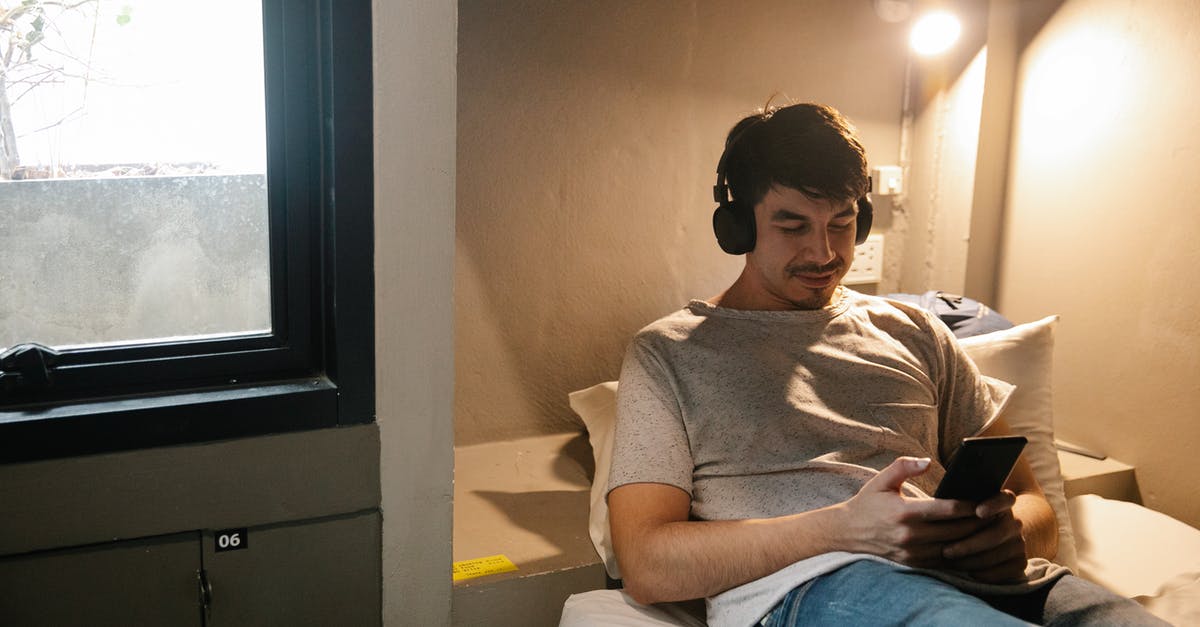 Journey planner for finding intercity train connections in China? - Smiling man resting on bed and using smartphone and headphones Journey planner for finding intercity train connections in China? - Smiling man resting on bed and using smartphone and headphones