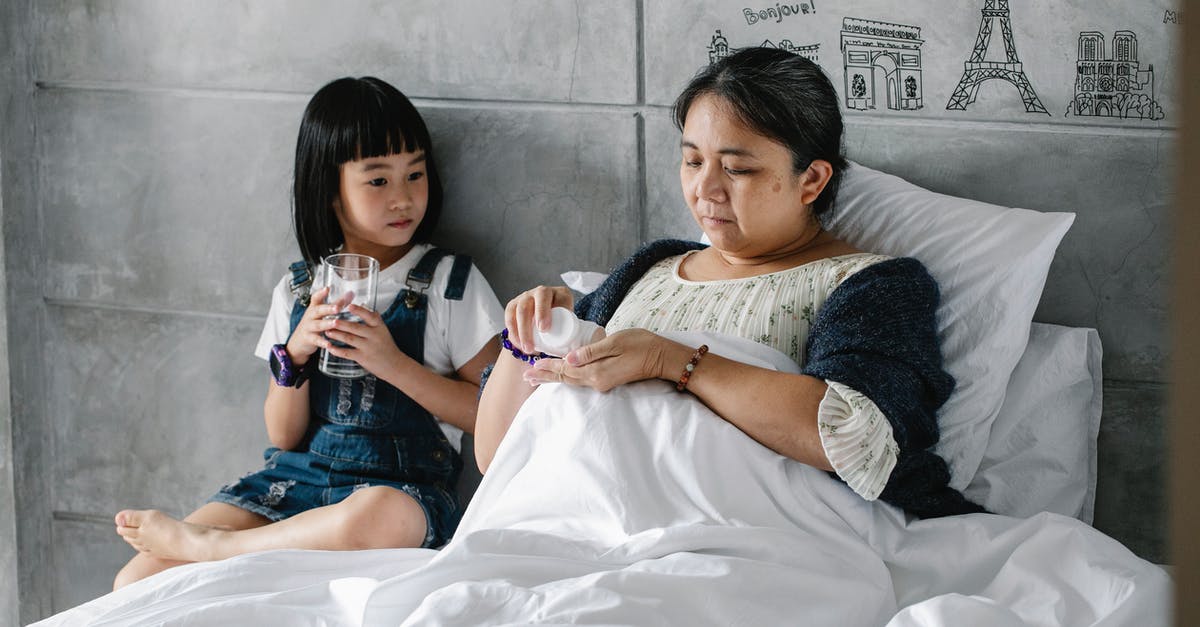 Just what is unhealthy in the water in Mexico? - Focused little Asian girl sitting on bed near sick grandmother drinking pills Just what is unhealthy in the water in Mexico? - Focused little Asian girl sitting on bed near sick grandmother drinking pills