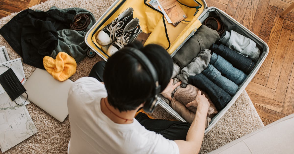 Laptop in a suitcase - A Man Listening on His Headphones while Packing His Clothes Laptop in a suitcase - A Man Listening on His Headphones while Packing His Clothes