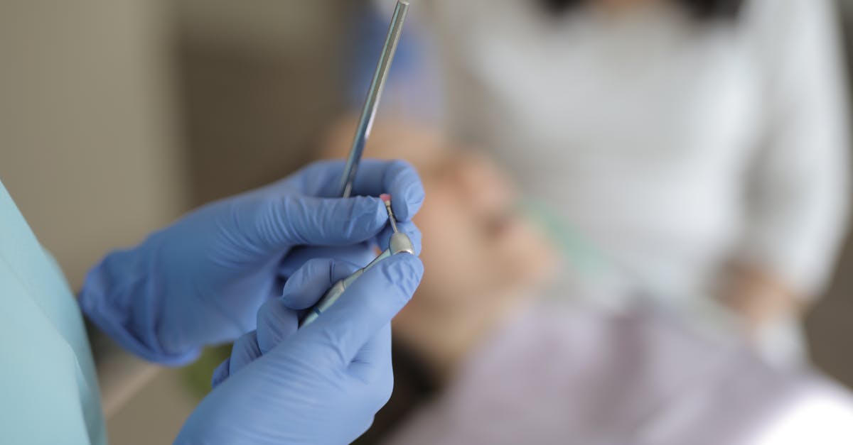 Larger metal objects in hand luggage - Unrecognizable crop dentist in latex gloves holding metal tools while standing in dental room during work with patient in modern clinic Larger metal objects in hand luggage - Unrecognizable crop dentist in latex gloves holding metal tools while standing in dental room during work with patient in modern clinic