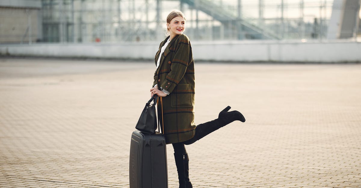 Lay over at El Prat Barcelona, luggage and city tour - Full body of stylish female tourist in warm clothes and high heeled boots standing on background of blurred airport terminal with luggage and ladies bag Lay over at El Prat Barcelona, luggage and city tour - Full body of stylish female tourist in warm clothes and high heeled boots standing on background of blurred airport terminal with luggage and ladies bag