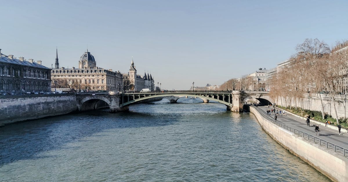 Leaving JFK with a French passport to enter Europe - Aged bridge above rippled river between old stone house exteriors under light sky in France Leaving JFK with a French passport to enter Europe - Aged bridge above rippled river between old stone house exteriors under light sky in France