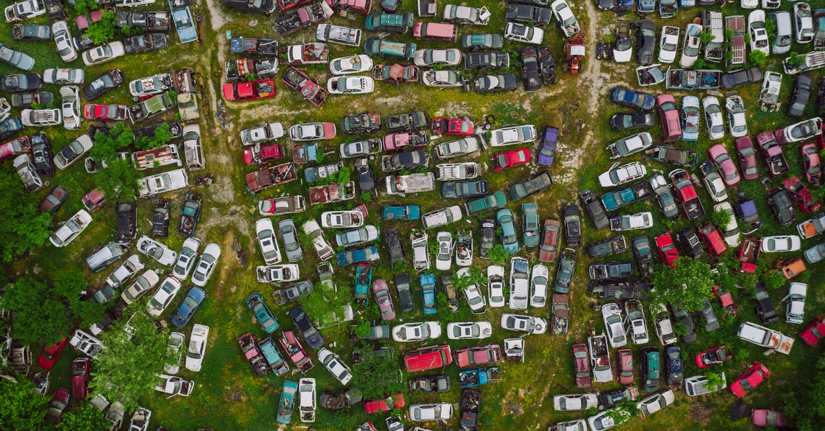 Leaving Sweden with a different passport? - Drone top view of old desolated vehicles of different colors in automobiles graveyard Leaving Sweden with a different passport? - Drone top view of old desolated vehicles of different colors in automobiles graveyard