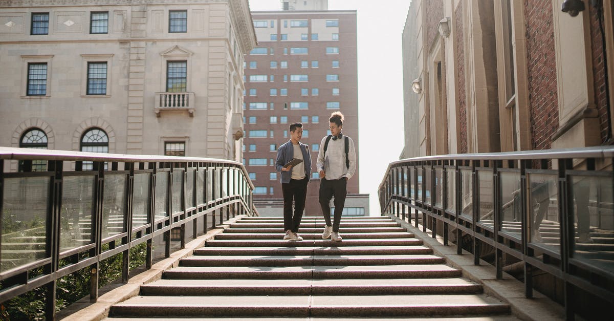 Length of stay in Schengen area - Full length of students in casual clothes walking downstairs and talking in residential district in city in daytime Length of stay in Schengen area - Full length of students in casual clothes walking downstairs and talking in residential district in city in daytime
