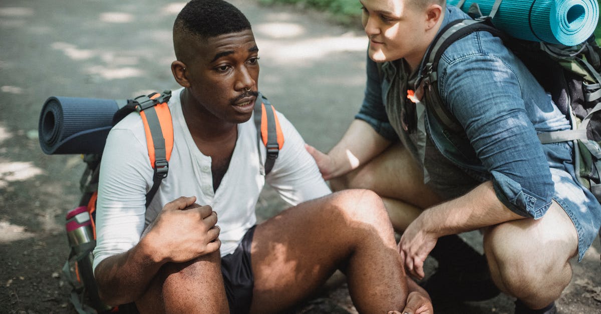 Limited Stay but difficult to travel - Black man resting on ground during hike with friend Limited Stay but difficult to travel - Black man resting on ground during hike with friend