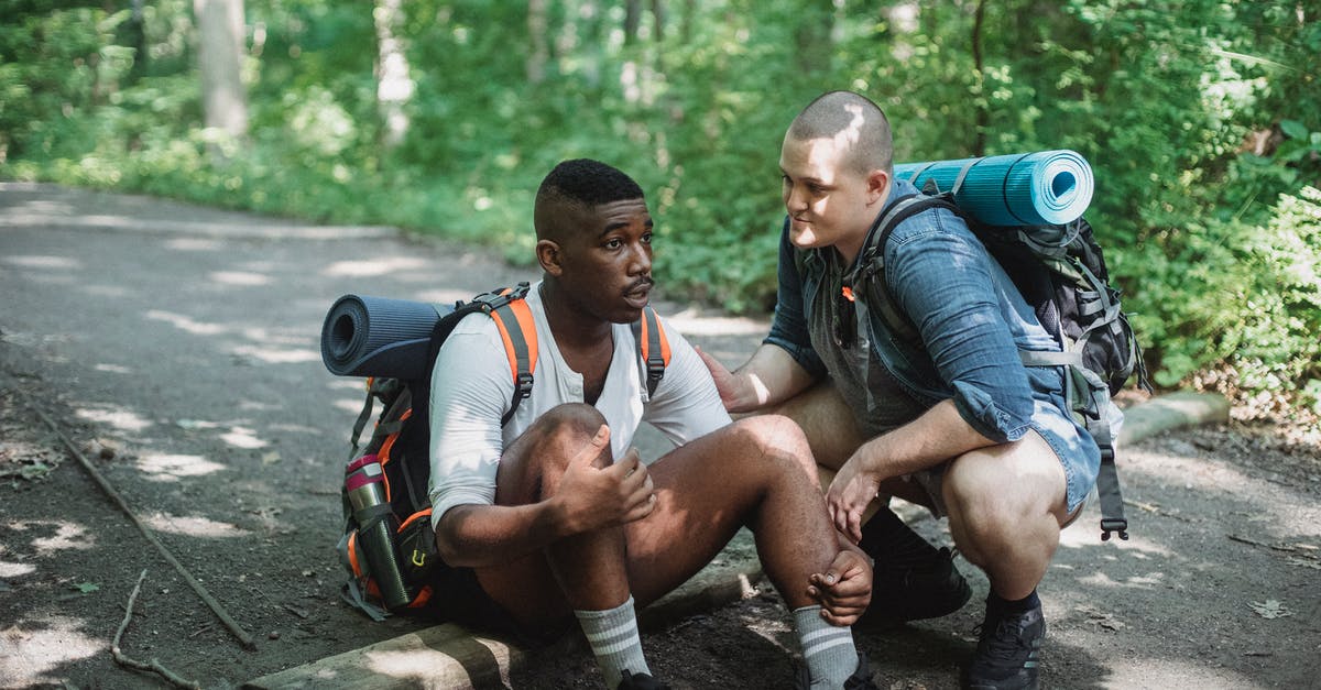 Limited Stay but difficult to travel - Black exhausted tourist resting on ground with friend Limited Stay but difficult to travel - Black exhausted tourist resting on ground with friend