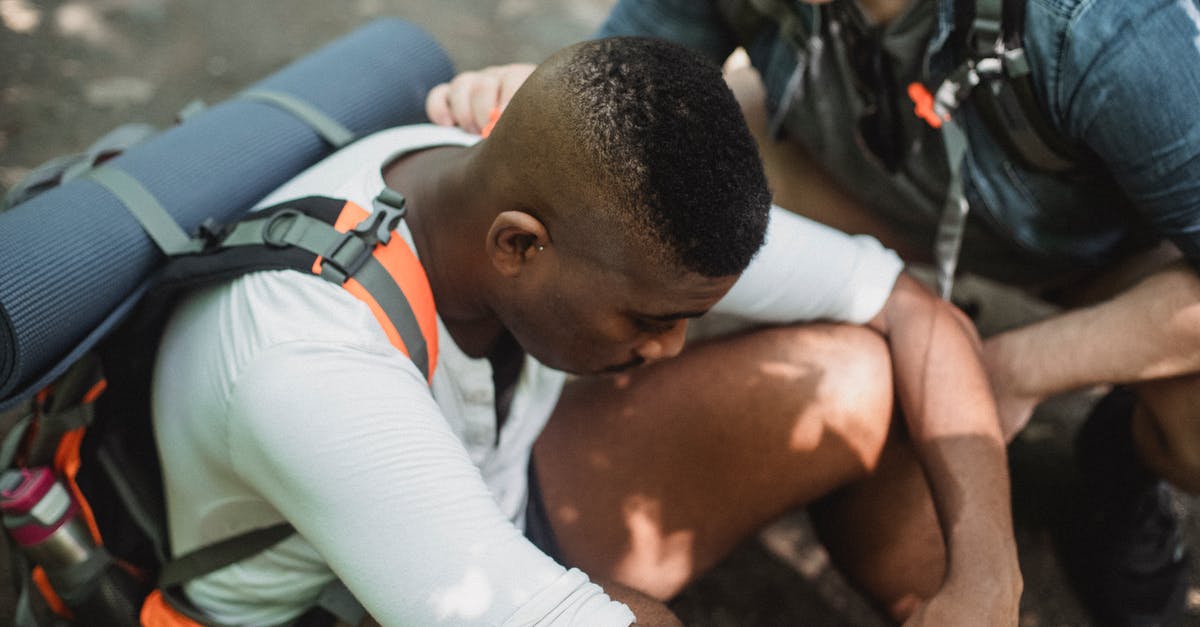 Limited Stay but difficult to travel - From above of man supporting tired African American friend exhausted while trekking in wildlife Limited Stay but difficult to travel - From above of man supporting tired African American friend exhausted while trekking in wildlife