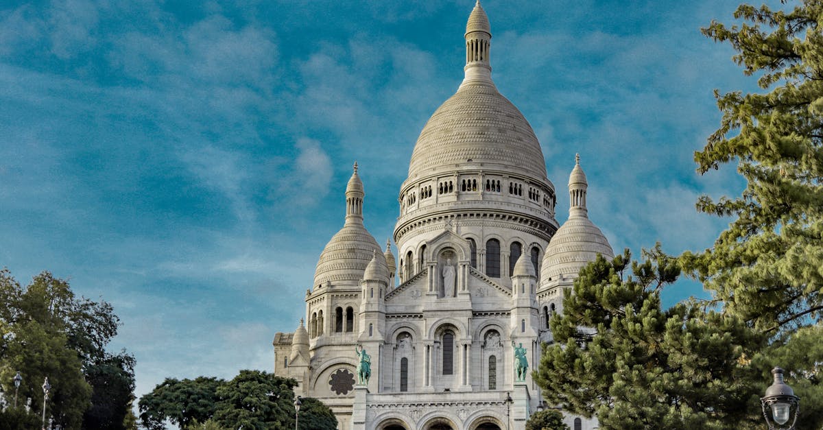 Location of Air France's lounges in Paris Charles de Gaulle Airport, France? - Low angle exterior of famous Sacre Coeur Basilica with domes and arched windows located on Montmartre hill in Paris against blue sky Location of Air France's lounges in Paris Charles de Gaulle Airport, France? - Low angle exterior of famous Sacre Coeur Basilica with domes and arched windows located on Montmartre hill in Paris against blue sky