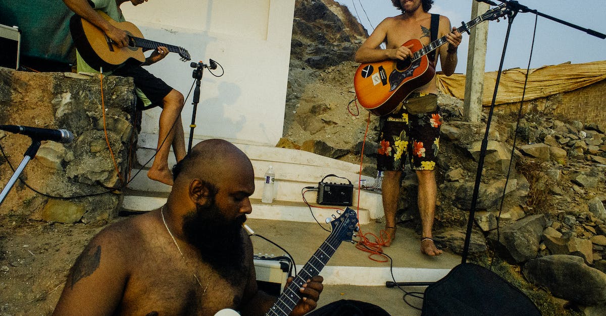 London clubs with nu-folk local bands - Local musical band of ethnic males in casual wear playing guitars outside shabby house in rural location