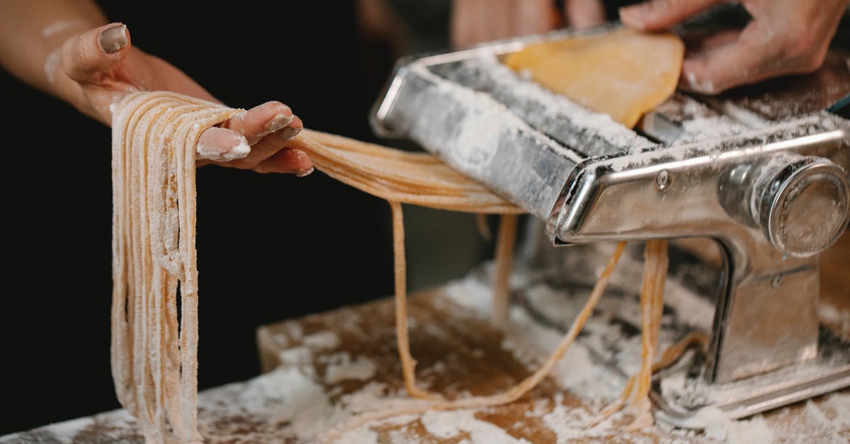 Long term Italian visa for Malaysian citizens - Crop anonymous female producing long noodle with metal pasta cutter on wooden table covered with flour Long term Italian visa for Malaysian citizens - Crop anonymous female producing long noodle with metal pasta cutter on wooden table covered with flour