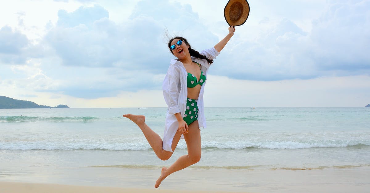 Long-term travel with youth mobility visa? - Woman Jumping on Seashore and Holding Hat
