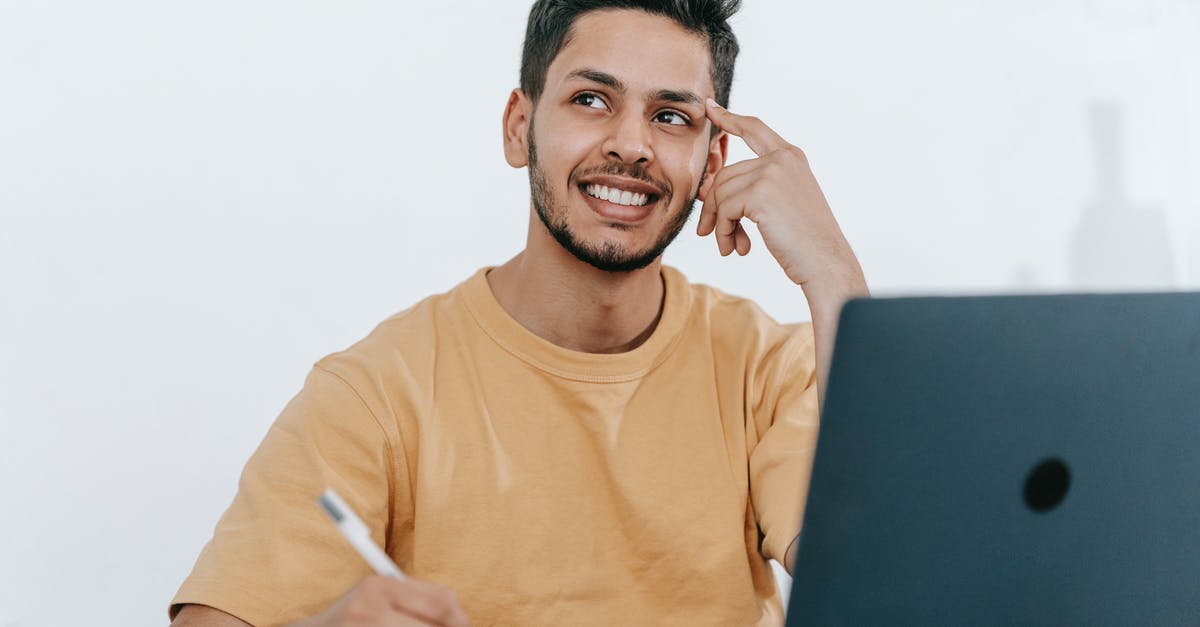 Looking for a good online itinerary organizer / travel planner [closed] - Smiling young bearded Hispanic male entrepreneur thinking over new ideas for startup project and looking away dreamily while working at table with laptop and taking notes in notebook