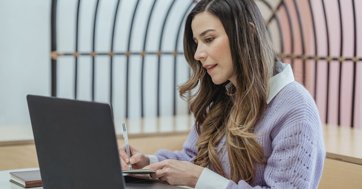 Looking for a good online itinerary organizer / travel planner [closed] - Focused female freelancer with wavy hair writing notes in planner while sitting at table and working on netbook