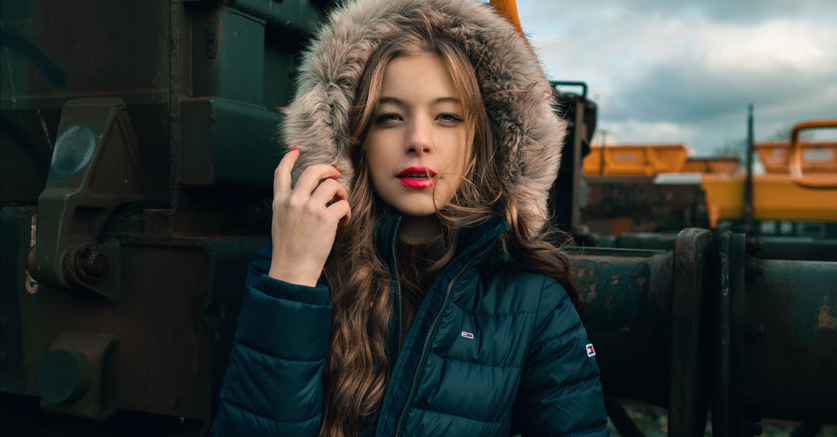 Luggage at transit - Serious young woman in warm clothes standing on railway near train and looking at camera