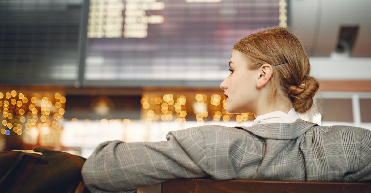 Major international passenger transit hubs near Luxembourg, other than Germany - Pensive female designer in checkered jacket waiting for flight near departure board looking away in modern airport in evening Major international passenger transit hubs near Luxembourg, other than Germany - Pensive female designer in checkered jacket waiting for flight near departure board looking away in modern airport in evening